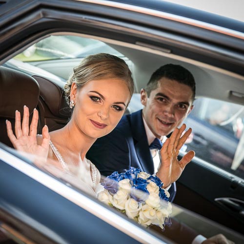 Para młoda po ceromonii ślubnej, w samochodzie weselnym